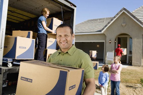 Professional movers transporting household items through a busy central London street